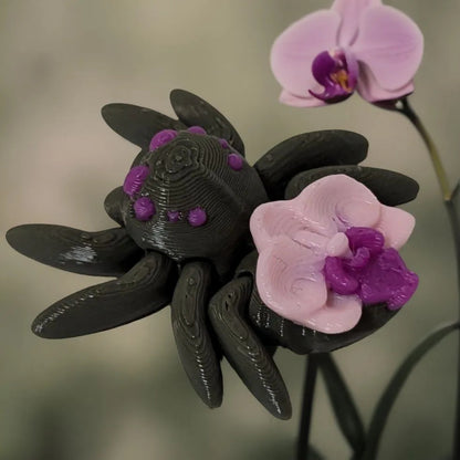 Mehrfarbige, flexible 3D-gedruckte Orchideenspinne mit Orchidee in Rosa und Magenta dem Rücken.