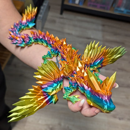 3D-gedruckter Kristalldrache mit Flügeln in Regenbogenfarben auf der Hand